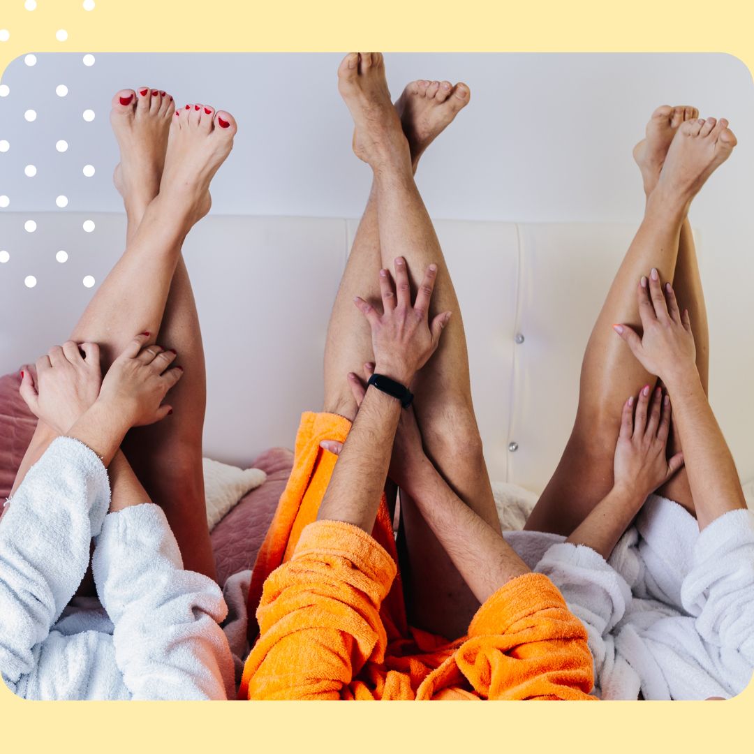 three pairs of legs in colourful towels on a couch with a yellow border.